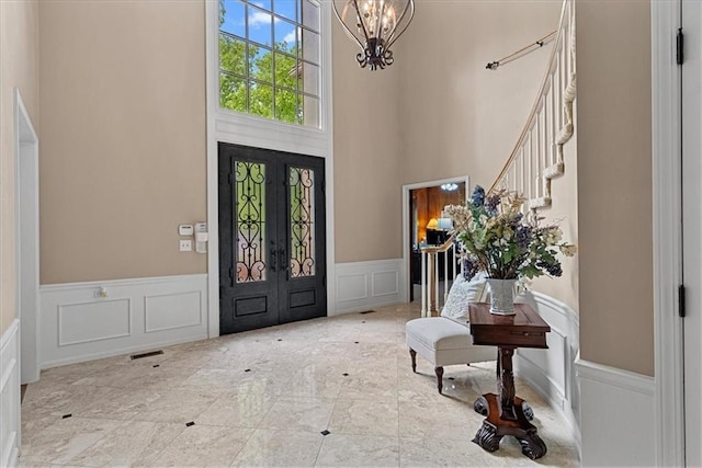 12613 Sherwood St, Leawood, KS 66209 - foyer entrance with a decorative wall, wainscoting, a chandelier, a high ceiling, and stairs