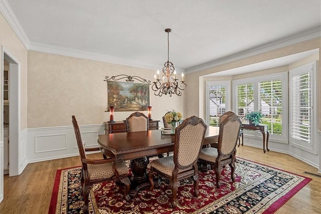 12613 Sherwood St, Leawood, KS 66209 - dining space featuring light wood-style flooring, a chandelier, ornamental molding, and wainscoting