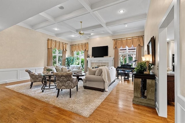 12613 Sherwood St, Leawood, KS 66209 - living area featuring healthy amount of natural light, light wood-style flooring, beamed ceiling, a ceiling fan, and a tiled fireplace