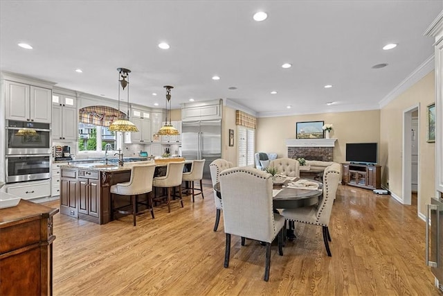 12613 Sherwood St, Leawood, KS 66209 - dining space featuring crown molding, light wood-type flooring, recessed lighting, and a brick fireplace