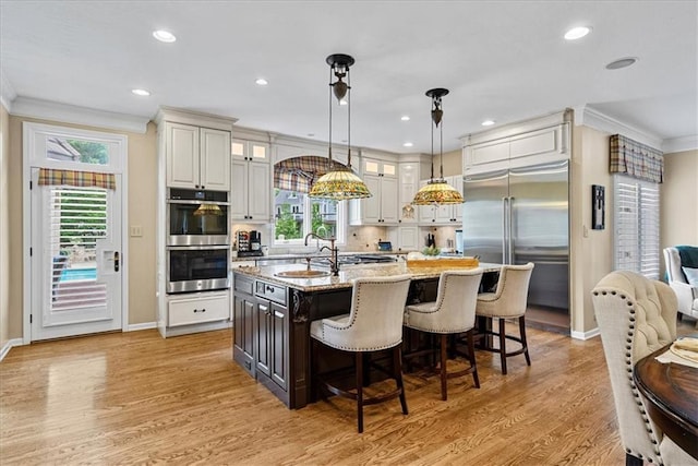 12613 Sherwood St, Leawood, KS 66209 - kitchen with appliances with stainless steel finishes, a sink, ornamental molding, baseboards, and an island with sink