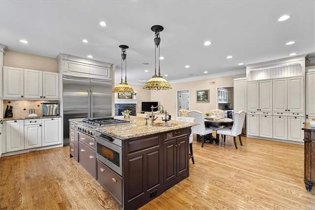12613 Sherwood St, Leawood, KS 66209 - kitchen featuring white cabinetry, a center island with sink, light wood-type flooring, decorative backsplash, and crown molding
