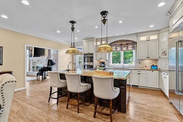 12613 Sherwood St, Leawood, KS 66209 - kitchen with light stone counters, stainless steel appliances, an island with sink, light wood-type flooring, and recessed lighting