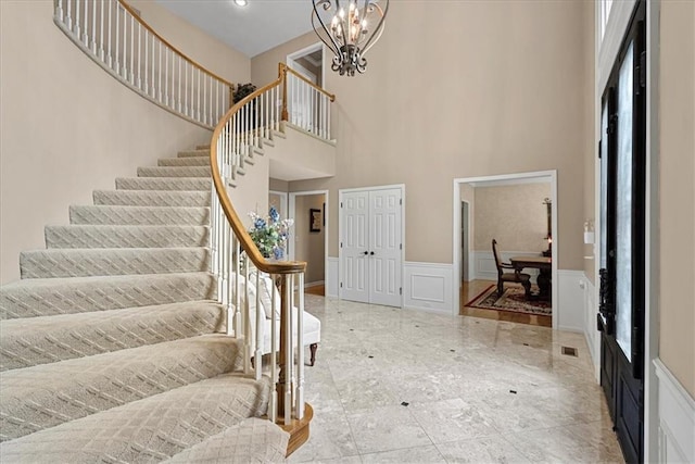 12613 Sherwood St, Leawood, KS 66209 - foyer entrance with stairway, a decorative wall, a high ceiling, a chandelier, and wainscoting