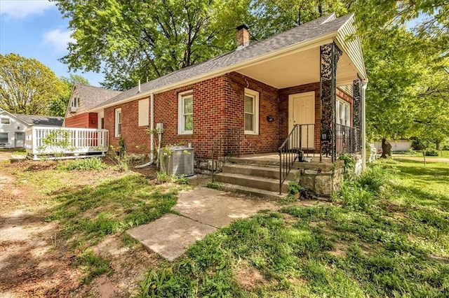 315 S Crane St S, Independence, MO 64050 - view of front of house with central air condition unit, brick siding, a chimney, and roof with shingles