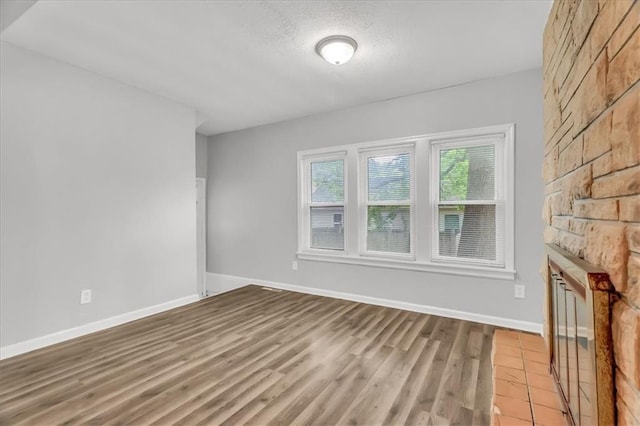 315 S Crane St S, Independence, MO 64050 - unfurnished living room with light wood-type flooring, baseboards, a large fireplace, and a textured ceiling