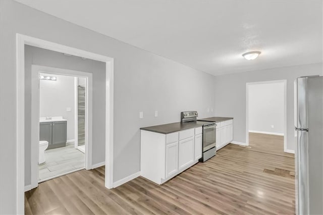 315 S Crane St S, Independence, MO 64050 - kitchen with stainless steel appliances, light wood-style flooring, white cabinetry, dark countertops, and baseboards