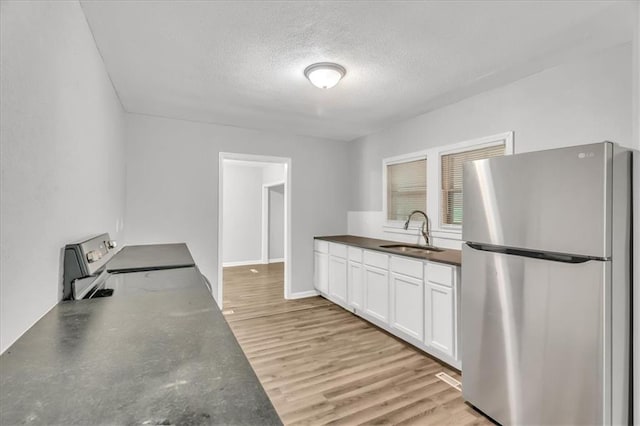 315 S Crane St S, Independence, MO 64050 - kitchen with freestanding refrigerator, a sink, dark countertops, a textured ceiling, and white cabinets