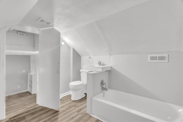 315 S Crane St S, Independence, MO 64050 - full bathroom featuring wood finished floors, toilet, lofted ceiling, a bath, and a textured ceiling
