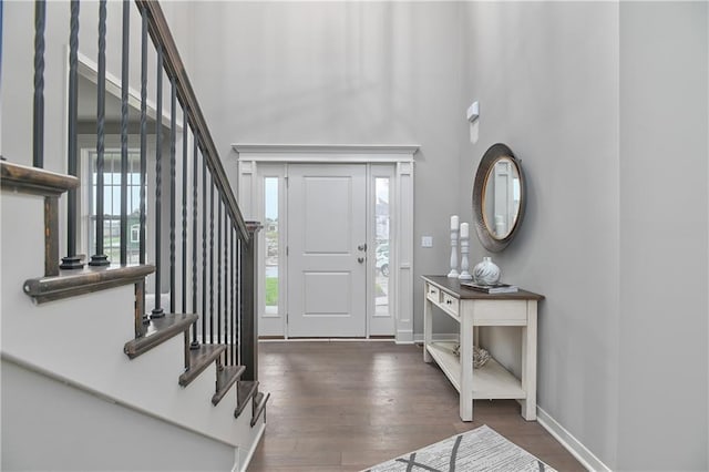 entrance foyer with stairs, a high ceiling, wood finished floors, and baseboards
