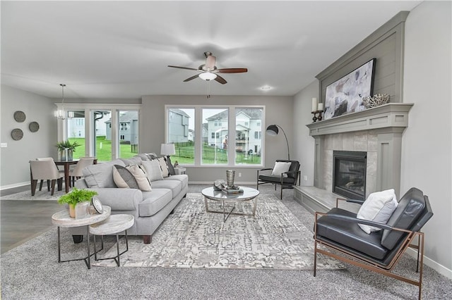 living room featuring baseboards, a tiled fireplace, and ceiling fan