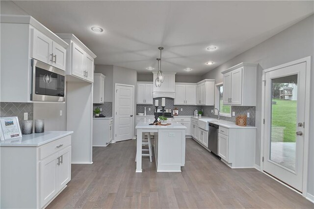 kitchen featuring stainless steel appliances, a sink, backsplash, white cabinetry, and recessed lighting
