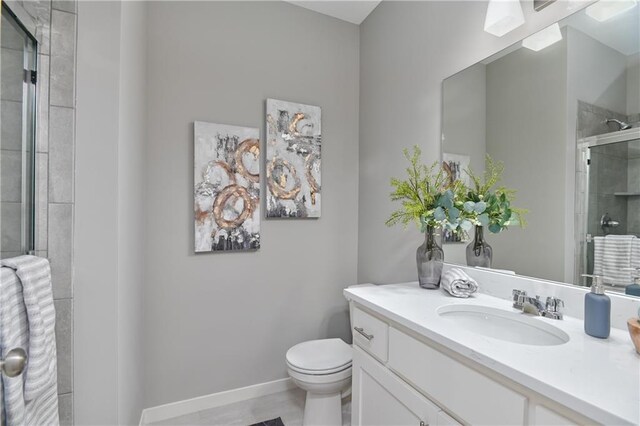 full bathroom with a tile shower, vanity, toilet, and baseboards