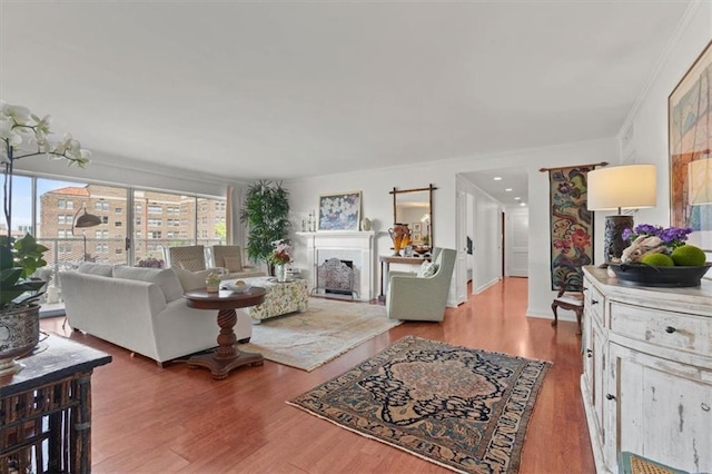 living room featuring wood finished floors, ornamental molding, and a fireplace