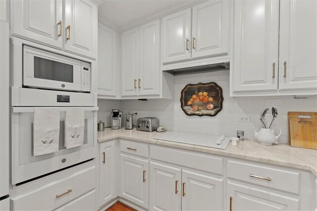kitchen featuring white appliances, white cabinetry, and decorative backsplash