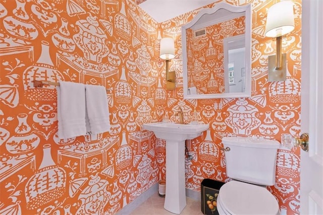 bathroom with tile patterned flooring, toilet, and wallpapered walls