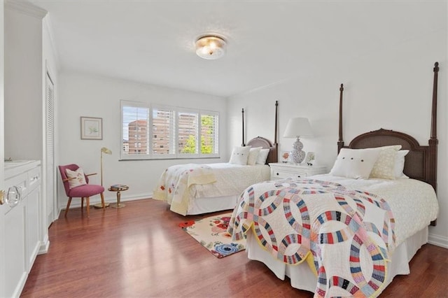bedroom featuring wood finished floors, baseboards, and a closet
