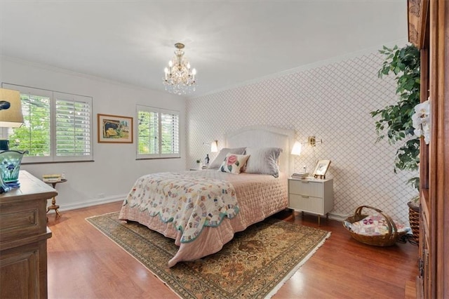 bedroom featuring ornamental molding, a chandelier, baseboards, wallpapered walls, and wood finished floors