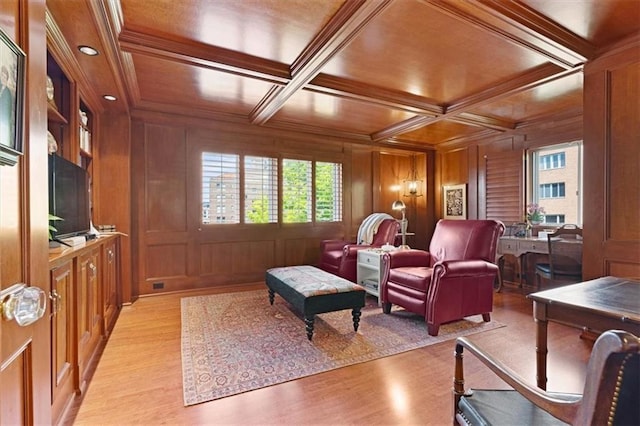 living area featuring light wood-style flooring, crown molding, coffered ceiling, beamed ceiling, and a decorative wall