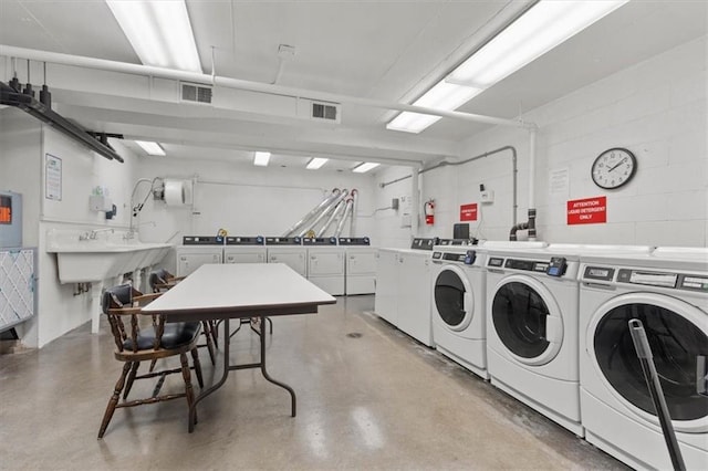 community laundry with separate washer and dryer and concrete block wall