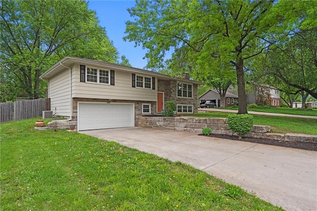 split foyer home featuring an attached garage, cooling unit, a chimney, concrete driveway, and stone siding
