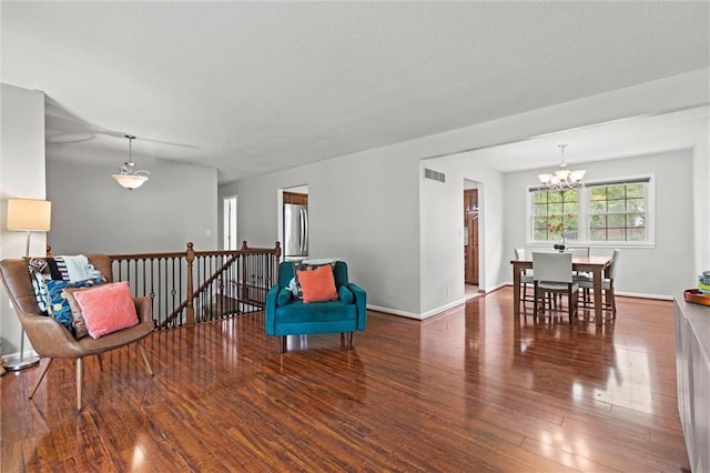 sitting room with an upstairs landing, a chandelier, wood finished floors, and baseboards