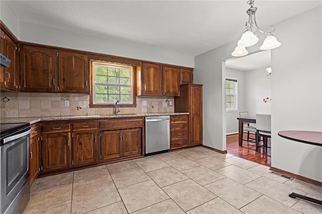 kitchen with appliances with stainless steel finishes, a sink, tasteful backsplash, and healthy amount of natural light