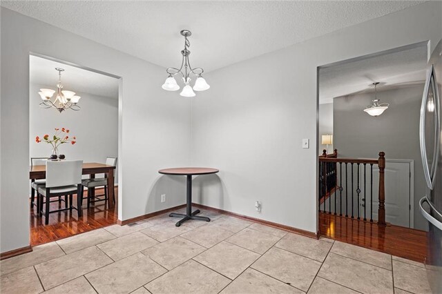 dining room with a chandelier, light tile patterned floors, a textured ceiling, and baseboards