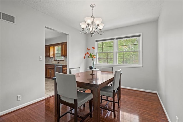 dining room featuring a chandelier, baseboards, dark wood-style flooring, and a textured ceiling