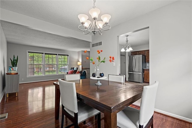 dining room featuring a chandelier, wood finished floors, baseboards, and a textured ceiling