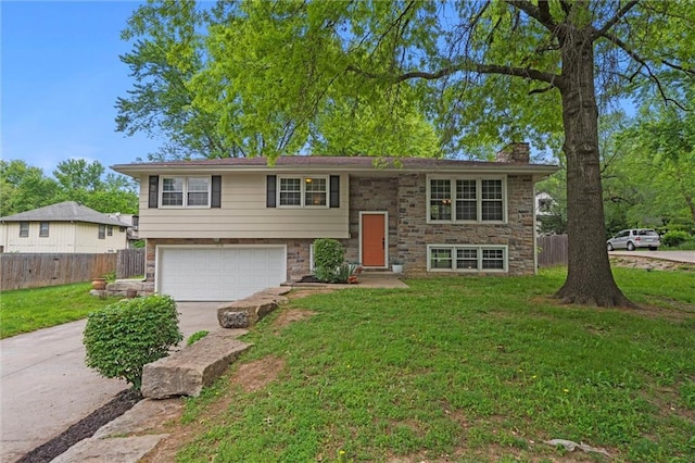 split foyer home with a chimney, concrete driveway, a garage, and stone siding
