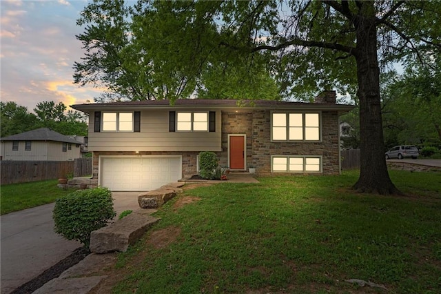 bi-level home featuring an attached garage, concrete driveway, a chimney, and stone siding