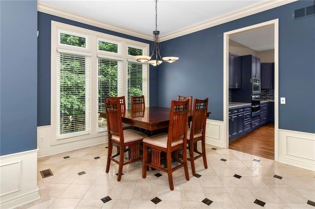 12843 Noland St, Overland Park, KS 66213 - dining space featuring a decorative wall, light tile patterned floors, a chandelier, a wainscoted wall, and crown molding