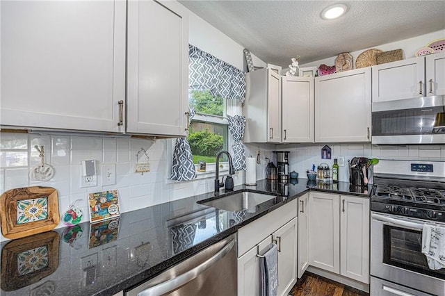 6405 Haskell Ave, Kansas City, KS 66104 - kitchen featuring appliances with stainless steel finishes, a sink, a textured ceiling, tasteful backsplash, and dark stone counters