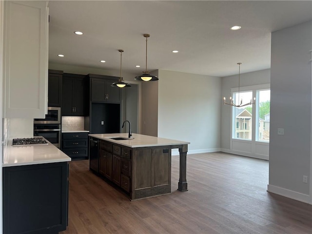 kitchen featuring a sink, appliances with stainless steel finishes, baseboards, wood finished floors, and recessed lighting