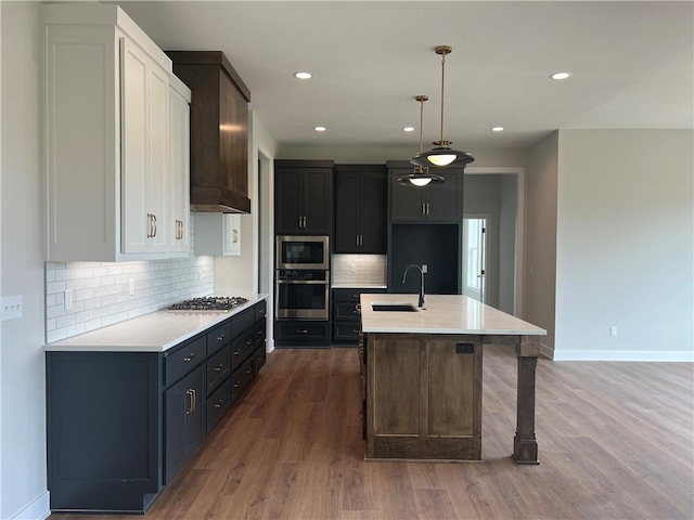kitchen featuring appliances with stainless steel finishes, a sink, light countertops, baseboards, and recessed lighting