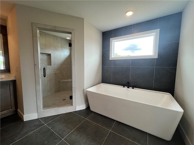 full bath with a shower stall, a freestanding tub, tile patterned floors, baseboards, and vanity