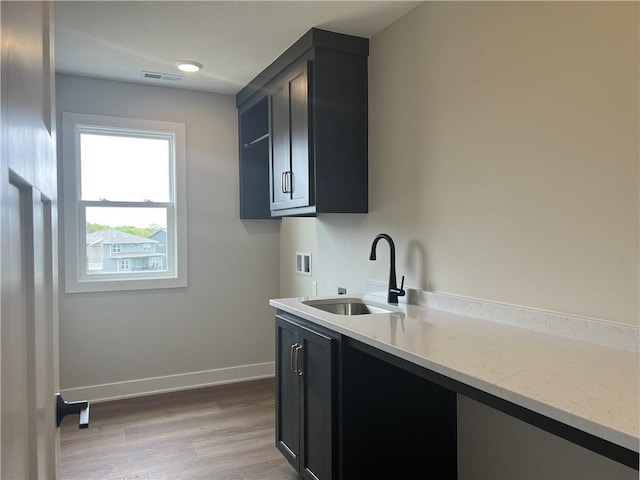 laundry area with hookup for a washing machine, baseboards, wood finished floors, and cabinet space