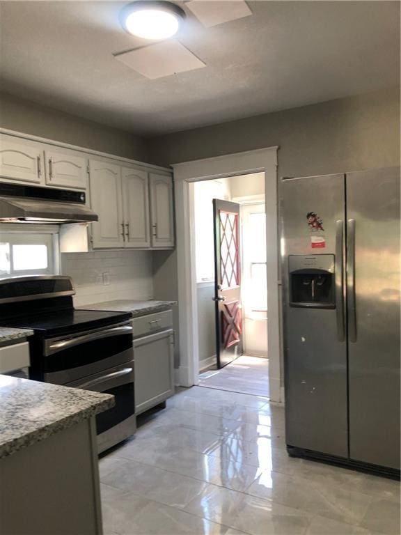 2063 Springfield Blvd, Kansas City, KS 66101 - kitchen featuring appliances with stainless steel finishes, under cabinet range hood, light stone counters, decorative backsplash, and white cabinetry
