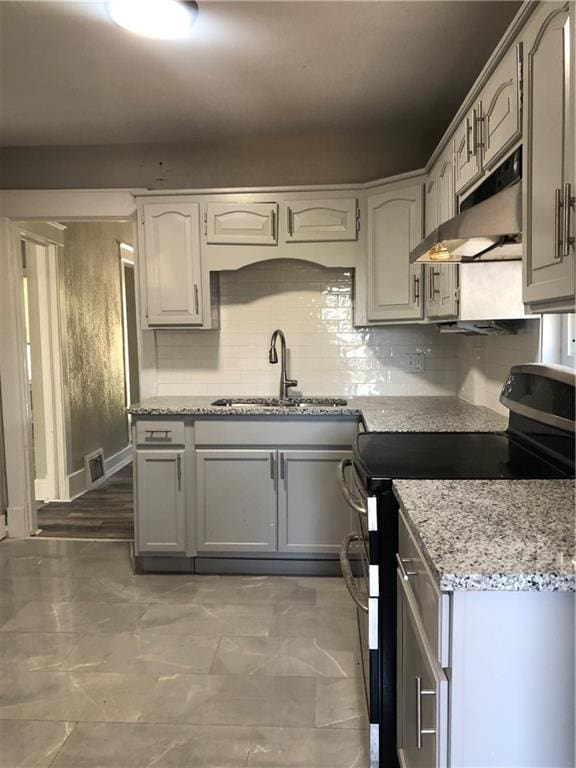 2063 Springfield Blvd, Kansas City, KS 66101 - kitchen with stainless steel electric range oven, under cabinet range hood, a sink, light stone countertops, and decorative backsplash
