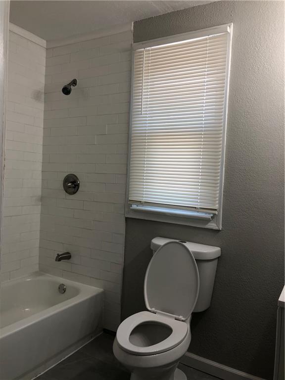 2063 Springfield Blvd, Kansas City, KS 66101 - bathroom featuring toilet, tile patterned flooring, shower / bathtub combination, and baseboards