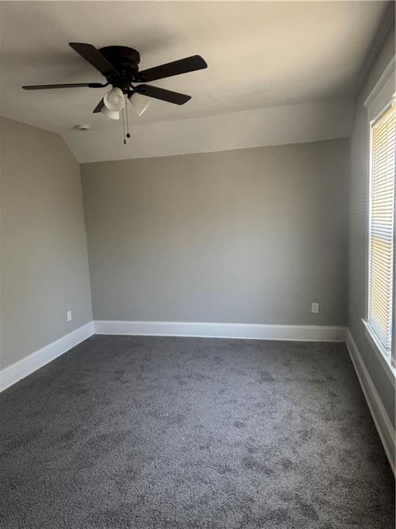 2063 Springfield Blvd, Kansas City, KS 66101 - unfurnished room featuring dark carpet, a ceiling fan, baseboards, and lofted ceiling