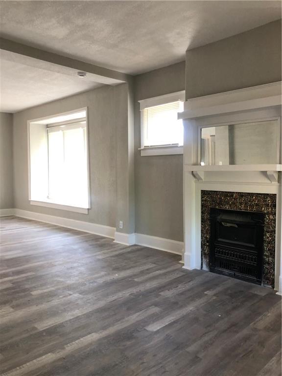 2063 Springfield Blvd, Kansas City, KS 66101 - unfurnished living room featuring dark wood-type flooring, baseboards, and a high end fireplace