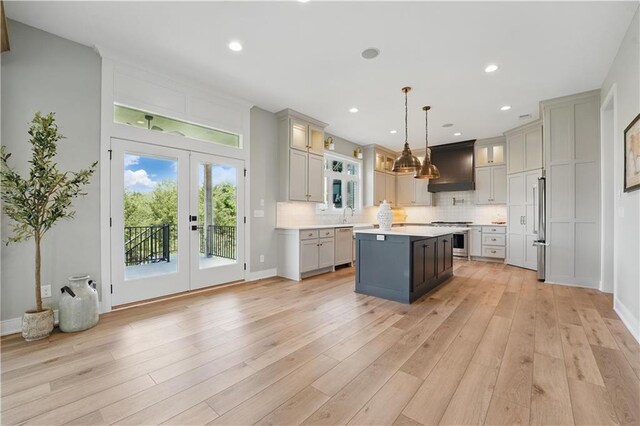 11588 S Houston St, Olathe, KS 66061 - kitchen with appliances with stainless steel finishes, a kitchen island, light countertops, ventilation hood, and decorative backsplash