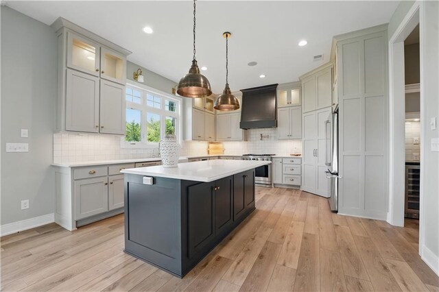 11588 S Houston St, Olathe, KS 66061 - kitchen with wine cooler, appliances with stainless steel finishes, a center island, light wood-style floors, and decorative backsplash