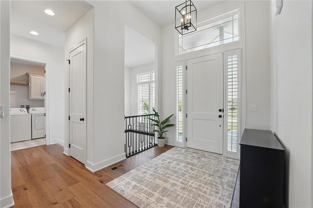 24765 W 89th Ter, Lenexa, KS 66227 - entrance foyer with washing machine and clothes dryer, wood finished floors, a chandelier, baseboards, and recessed lighting