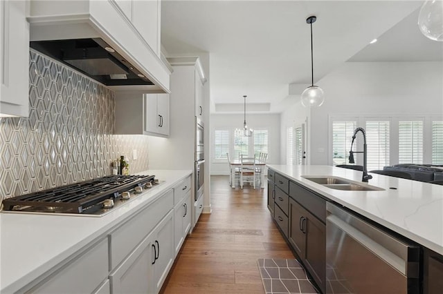 24765 W 89th Ter, Lenexa, KS 66227 - kitchen featuring a sink, appliances with stainless steel finishes, custom range hood, dark wood finished floors, and decorative light fixtures