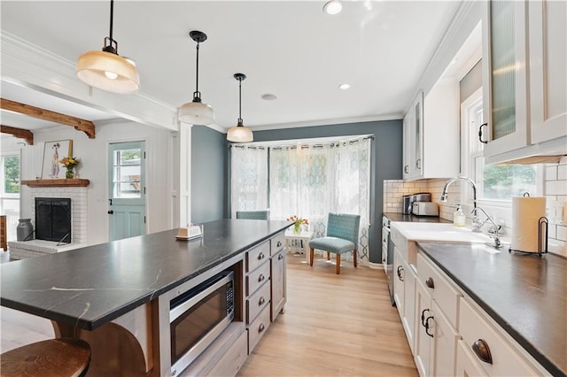 9849 Riggs St, Overland Park, KS 66212 - kitchen featuring stainless steel microwave, dark countertops, ornamental molding, decorative backsplash, and light wood-type flooring