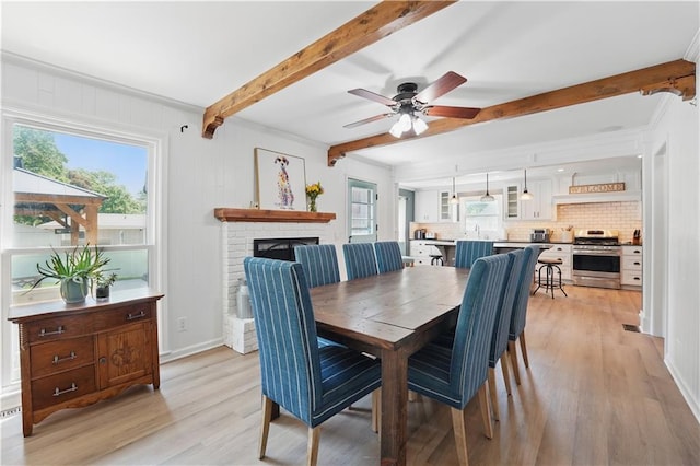 9849 Riggs St, Overland Park, KS 66212 - dining room with beamed ceiling, light wood-style floors, healthy amount of natural light, a ceiling fan, and a brick fireplace