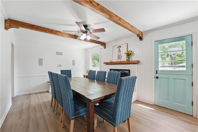 9849 Riggs St, Overland Park, KS 66212 - dining space with beam ceiling, light wood-style flooring, a fireplace, ceiling fan, and a decorative wall